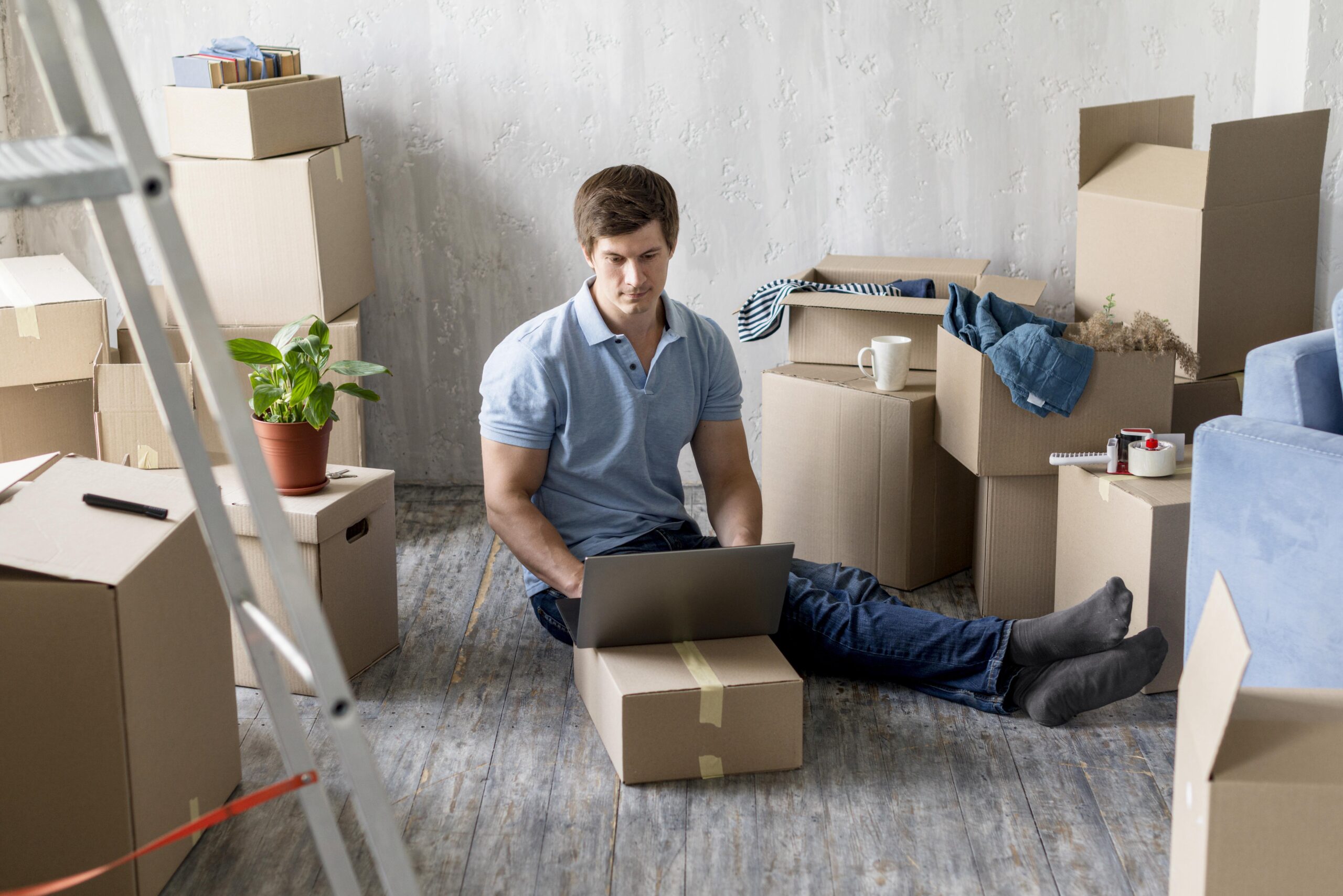 man working laptop with boxes ready move out